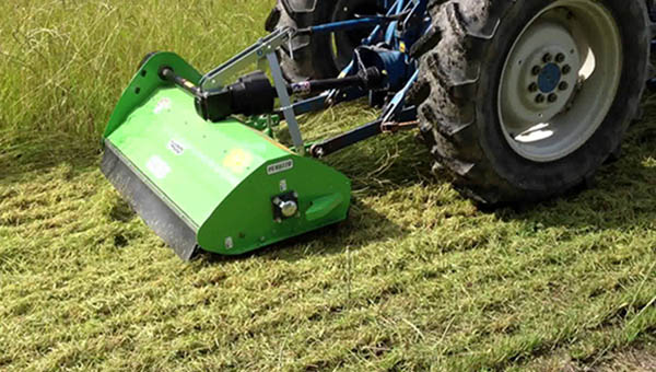 Мульчирующая косилка скашивает и измельчает траву на обочине дороги - уход за ландшафтом